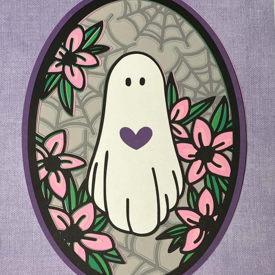 A square decorative graphic featuring a white ghost with a purple heart, surrounded by pink flowers and green leaves inside an oval frame on a purple textured background. Close up